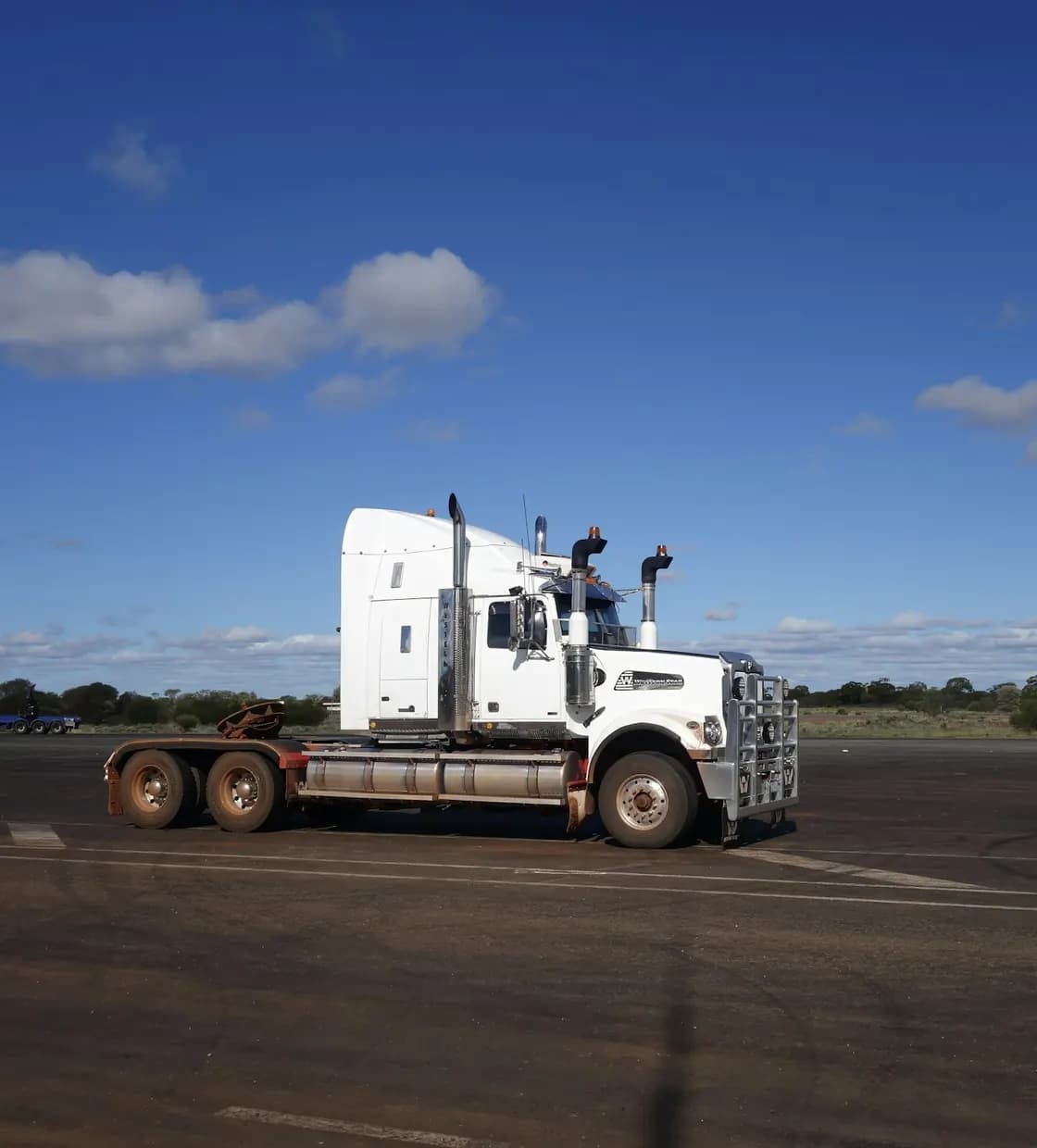 A white semi truck parked on an open lot under a blue sky