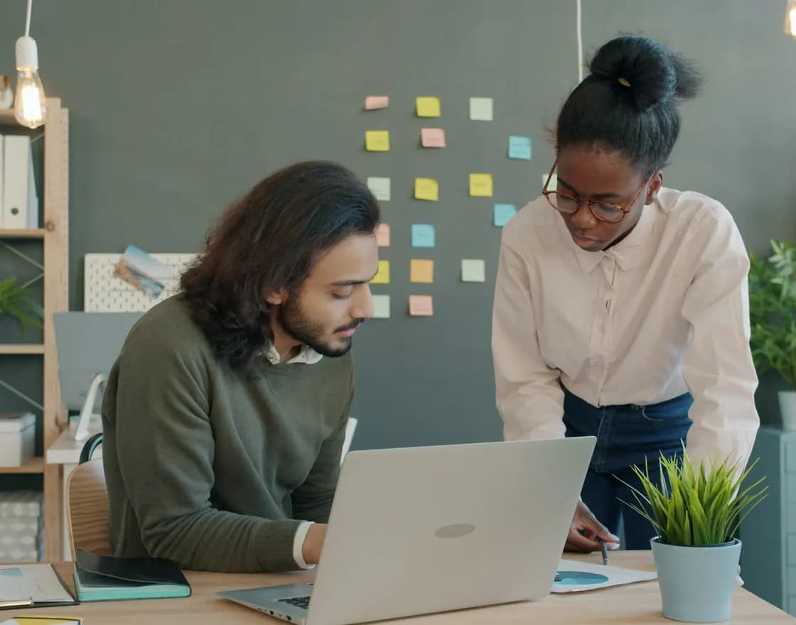 Two colleagues reviewing a file on a laptop in an office