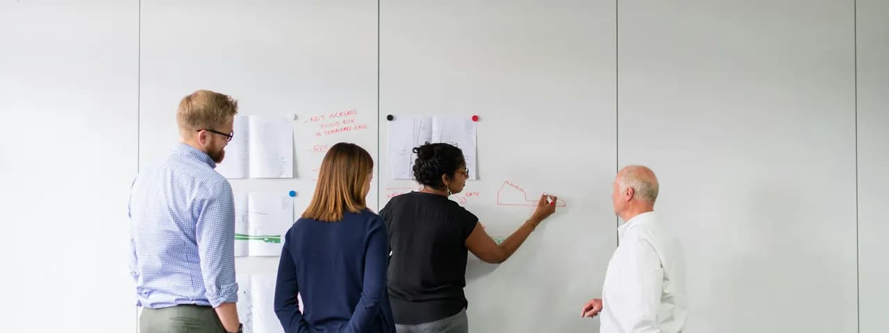 Four colleagues planning together at a whiteboard